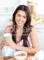Radiant asian woman holding a cup sitting at breakfast table