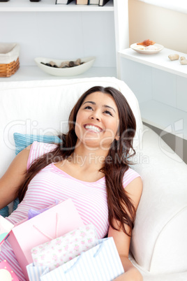 Cheerful asian woman sitting on her sofa with shopping bags