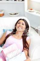 Cheerful asian woman sitting on her sofa with shopping bags