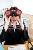 Astonished businesswoman looking through spyglasses