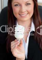 Happy businesswoman holding a light bulb smiling at the camera