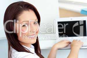 Charming businesswoman using her laptop smiling at the camera