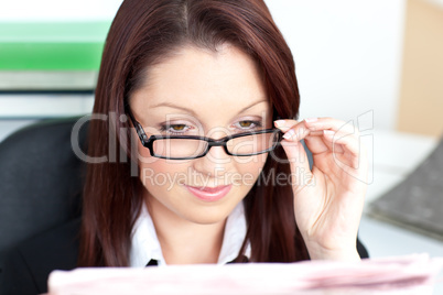 Delighted businesswoman reading a newspaper wearing glasses
