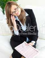 Elegant businesswoman holding a newspaper sitting on a sofa