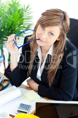 Thougtful businesswoman holding glasses sitting at her desk
