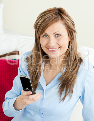 Beautiful businesswoman using her mobile phone sitting on a sofa