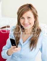 Beautiful businesswoman using her mobile phone sitting on a sofa