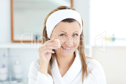 Radiant woman putting cream on her face