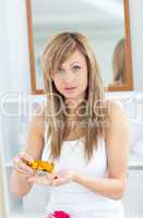 Caucasian blond woman taking pills looking at the camera