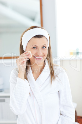 Charming woman putting cream on her face