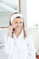 Charming woman putting cream on her face