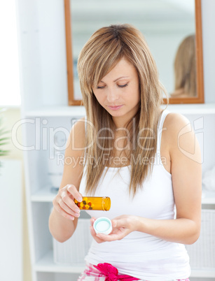 Serious woman taking pills in the bathroom