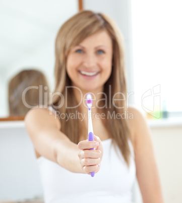 Smiling woman holding a toothbrush into the camera