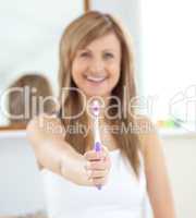 Smiling woman holding a toothbrush into the camera