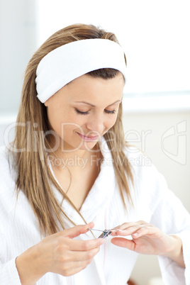 Concentrated woman using a nail scissors