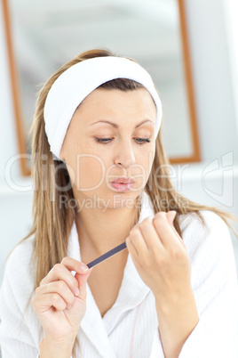 Caucasian woman doing her nails with a nail file
