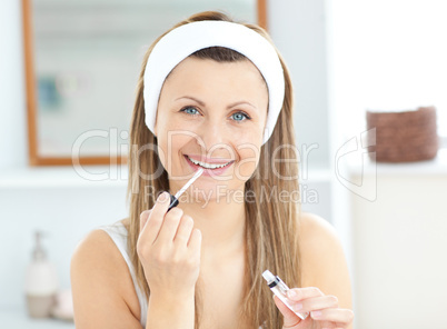 Glowing woman applying gloss on her lips wearing a headband