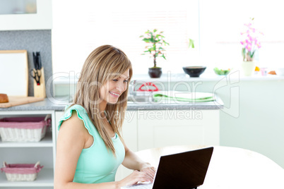 Bright woman using her laptop in the kitchen