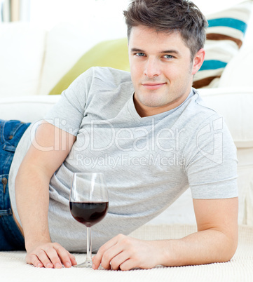 Handsome young man with wineglass lying on the floor