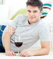 Handsome young man with wineglass lying on the floor