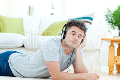 Charming young man listen to music lying on the floor