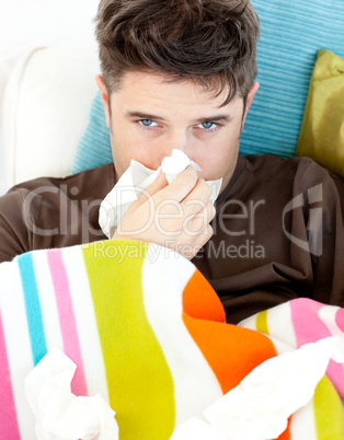 Diseased young man with tissues lying on the sofa