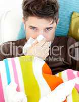 Diseased young man with tissues lying on the sofa
