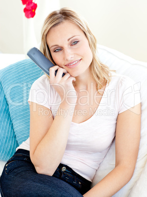 Glowing blond woman watching tv sitting on a sofa