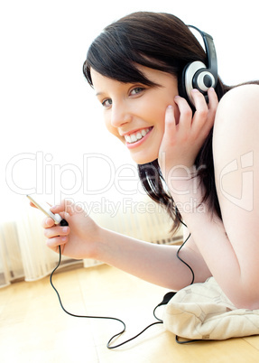 Positive caucasian teenager listen to music lying on the floor