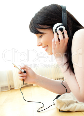 Jolly young woman listen to music lying on the floor