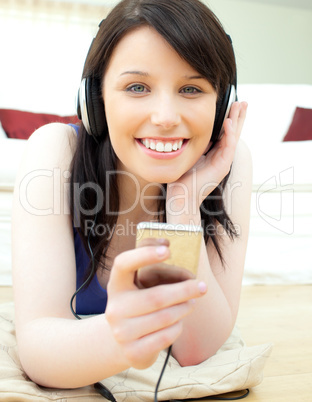 Glowing young woman listen to music lying on the floor