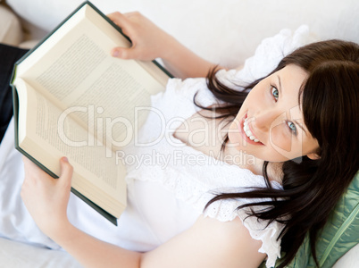 Bright brunette teenager holding a book smiling at the camera