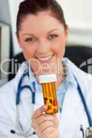 Delighted female doctor holding pills into the camera