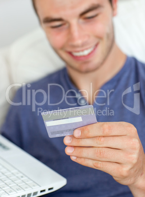 Close-up of a smiling man holding a card and a laptop