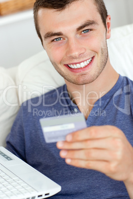 Close-up of a jolly man holding a card and a laptop
