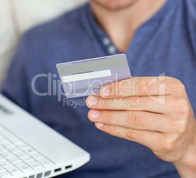 Close-up of a caucasian man holding a card and a laptop