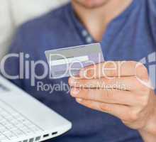 Close-up of a caucasian man holding a card and a laptop
