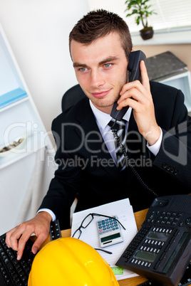 Caucasian young businessman talking on phone sitting at his desk