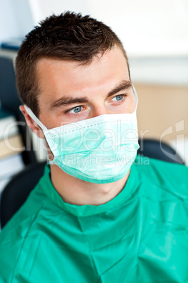 Serious male surgeon with mask and scrubs