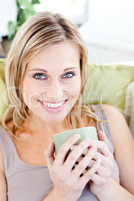 Positive blond woman holding a cup smiling at the camera