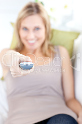 Relaxed woman lying on the sofa holding a remote