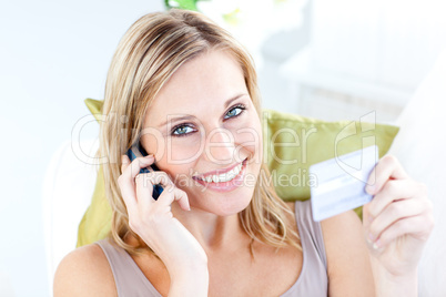 Charming young woman talking on phone holding a card