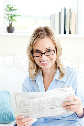 Bright businesswoman reading the newspaper sitting on the sofa