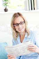 Attractive businesswoman reading the newspaper sitting on the so