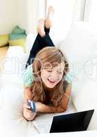 Cheerful caucasian woman using her laptop holding a card
