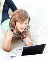 Joyful blond woman looking at her laptop on the sofa