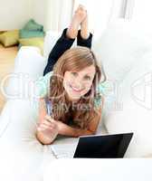 Bright caucasian woman lying on the sofa with laptop and card