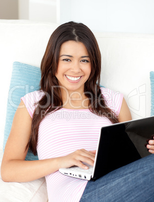 Beautiful asian woman using her laptop lying on the sofa