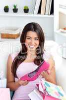 Cheerful young asian woman holding a shoe sitting between shoppi