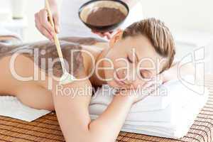 Relaxed woman enjoying a mud skin treatment